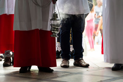 Lower part of catholic church members with incense in the campo santo cemetery 