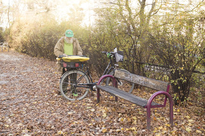 Senior man besides empty bench and against trees