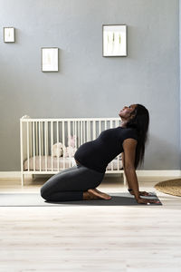 Side view of young woman lying on floor against wall