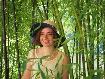 Portrait of smiling young woman standing against trees