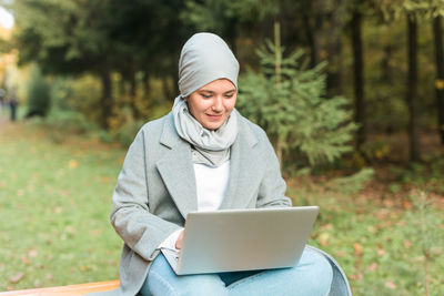 Smiling young woman using mobile phone in park