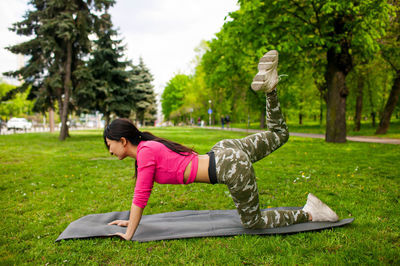 Asian girl exercising on mat in summer park