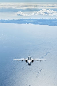 Airplane flying over sea against sky