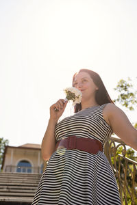 Portrait of a smiling young woman standing against clear sky