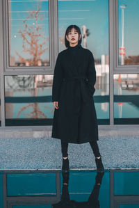 Portrait of woman standing against window