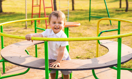 Portrait of happy boy playing on slide at playground