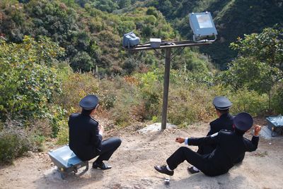 Men sitting against trees in forest