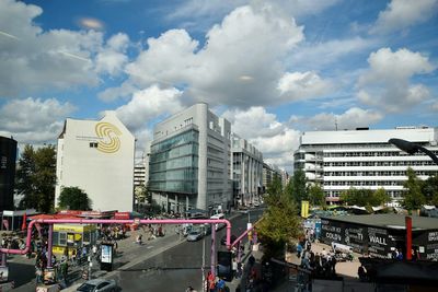 Road by buildings in city against sky