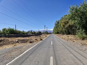 Empty road amidst field against sky