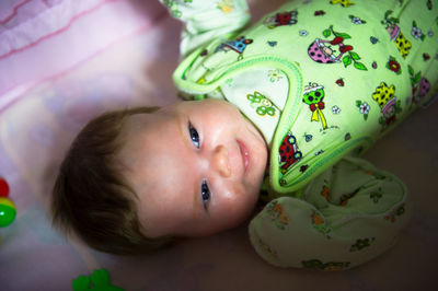 Portrait of cute baby boy lying on bed at home