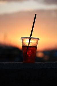 Close-up of wine glass against orange sunset