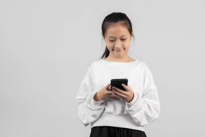 Mid adult woman using smart phone against white background