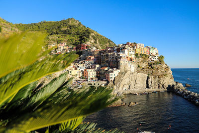 Scenic view of sea by buildings against clear blue sky