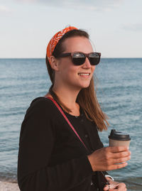 Pretty hipster woman walking on beach coffee cup lifestyle millennial girl drinking tea generationz 