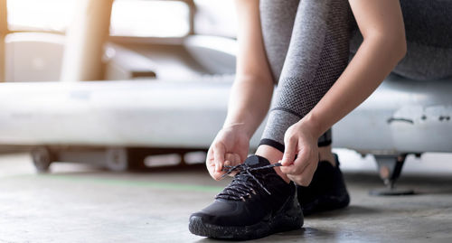 Low section of woman tying shoe lace