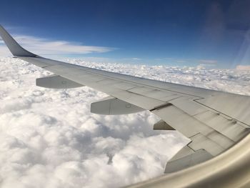 Airplane wing over clouds against blue sky