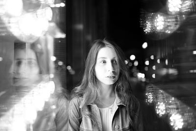 Beautiful woman looking away in illuminated city at night