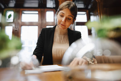 Confident mature female lawyer signing contract document in board room