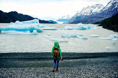 High angle view of woman standing overlooking icebergs at lago grey in patagonia, chile