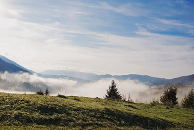 Beautiful early morning in mountains. blue sky with some clouds and fog on the hills