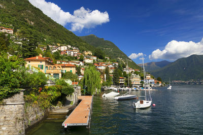 Boats at lake como by mountains against sky