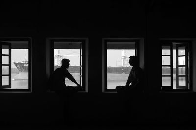 Side view of silhouette man sitting in glass window