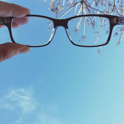 Low angle view of cropped hand against clear sky