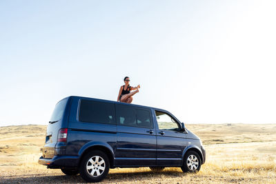 A young woman practicing yoga on the roof of a caravan in a rural land