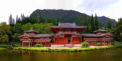 Traditional building by lake against sky