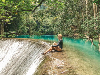 Side view of man in river against trees in forest