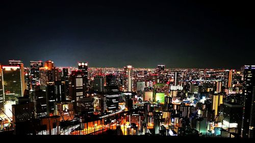 Illuminated cityscape against sky at night