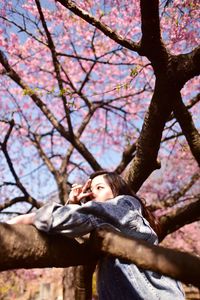 Low angle portrait of woman on tree