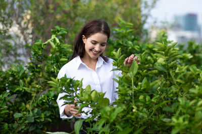 Portrait of a smiling young woman against plants