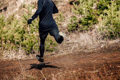 Male jogger run down mountain on muddy trail
