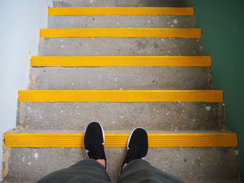 Low section of man standing on yellow shoes