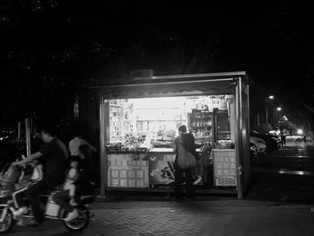 People on street against illuminated city at night