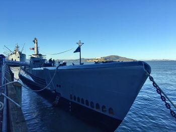 Ship moored on sea against clear blue sky