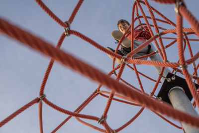 Kid on the top looking down after climbing the ropes in a playground