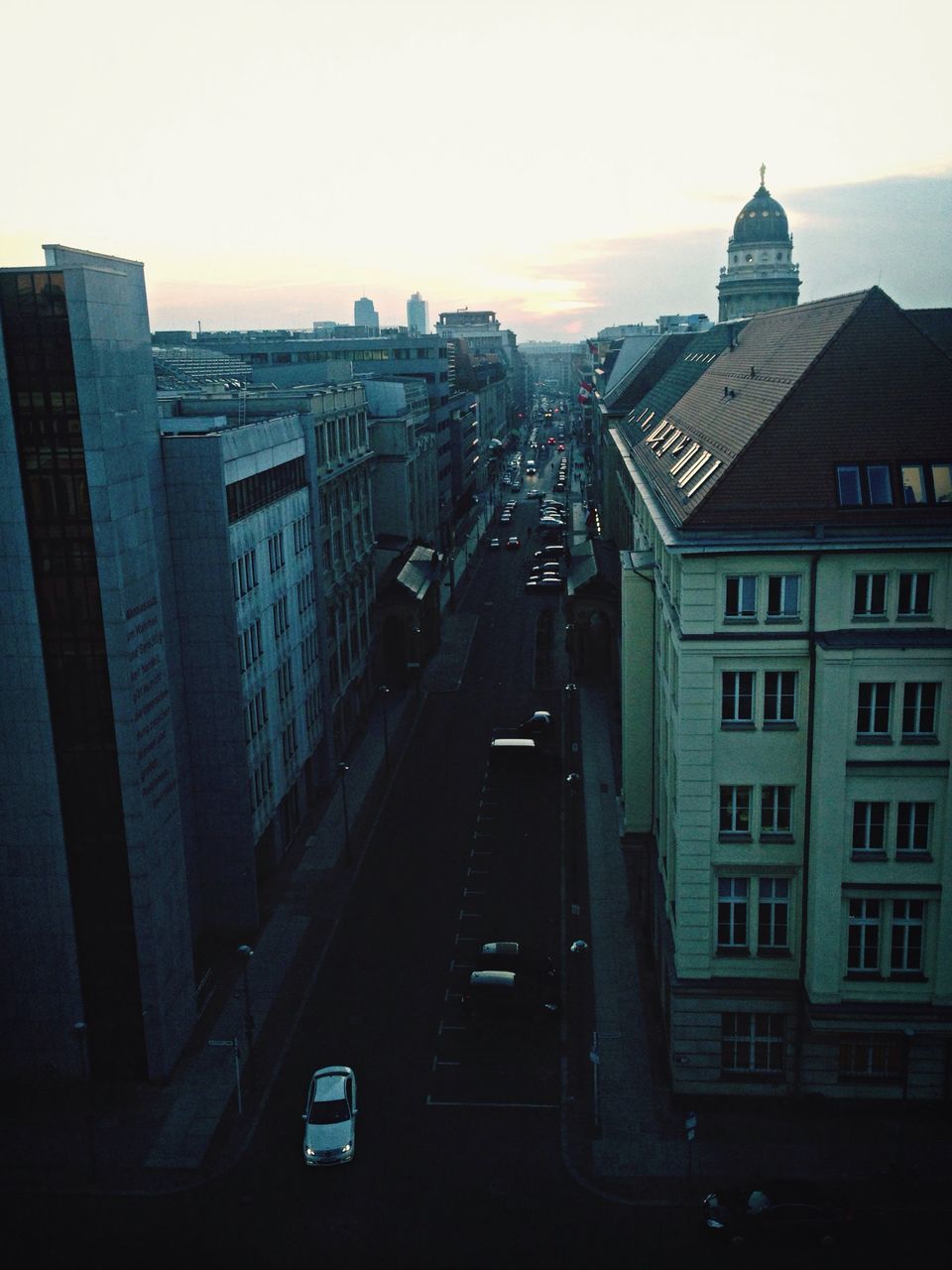 building exterior, architecture, built structure, city, transportation, sunset, high angle view, cityscape, car, mode of transport, land vehicle, road, sky, street, city life, skyscraper, building, clear sky, traffic, residential building