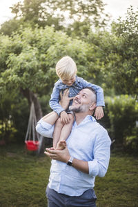 Happy father carrying son on shoulders in backyard