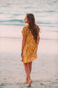Woman looking away while standing on beach
