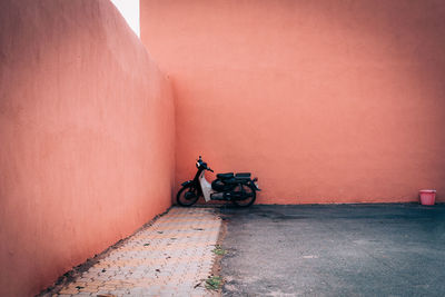 Man cycling on footpath against wall in city