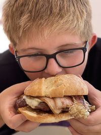 Close-up of young boy munching a burger. 