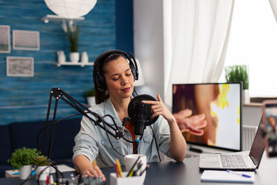 Woman wearing headphones doing podcast in office