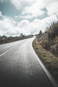 Road by trees against sky