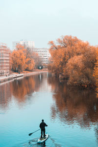 Rear view of man on lake against sky during autumn