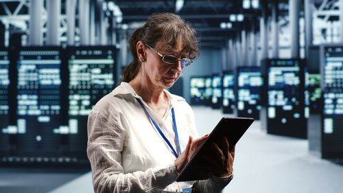 Young woman using digital tablet while standing in office