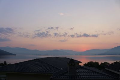 Houses by sea against sky during sunset