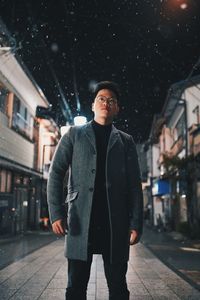 Portrait of young man standing in city during winter