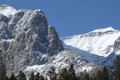 Low angle view of snowcapped mountains against clear blue sky